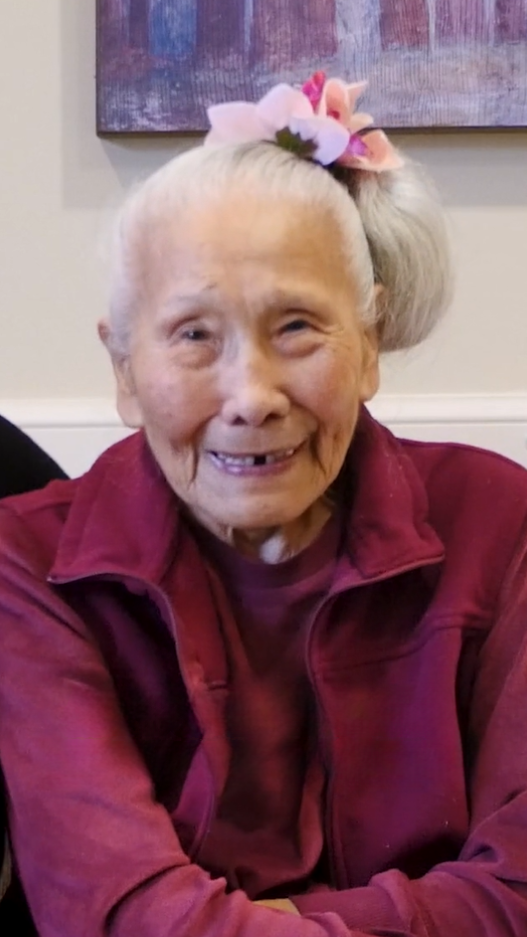 Senior woman with pink flower in her hair and red jacket