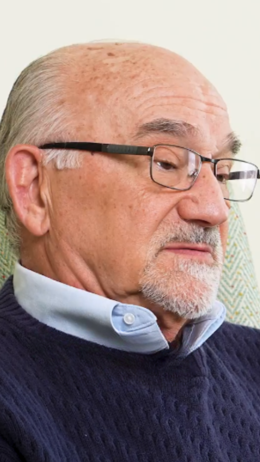 senior man in glasses and blue sweater with collard shirt underneath